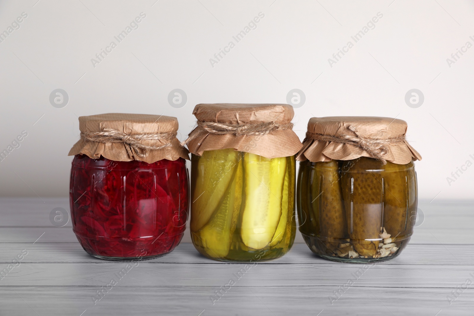 Photo of Jars with different preserved vegetables on wooden table