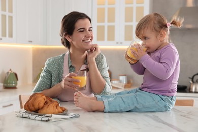 Photo of Mother and her little daughter having breakfast together in kitchen