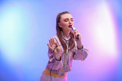 Emotional woman with microphone singing in color lights