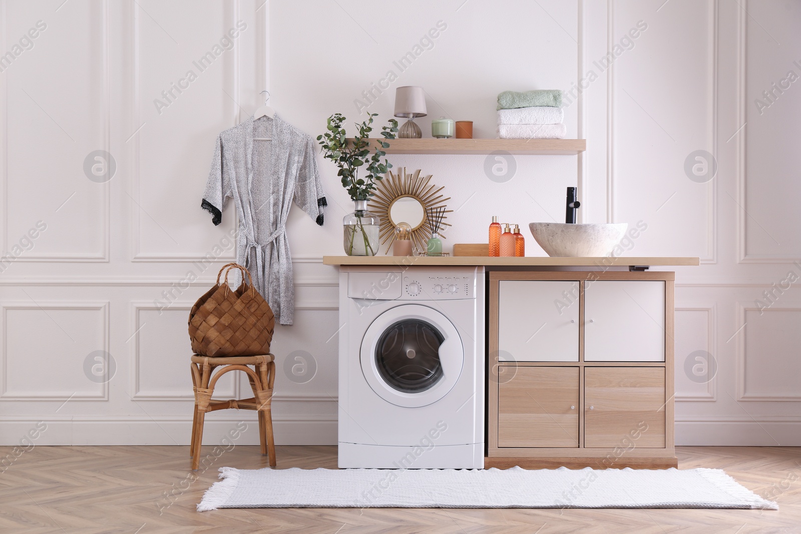 Photo of Laundry room interior with modern washing machine and stylish vessel sink on countertop