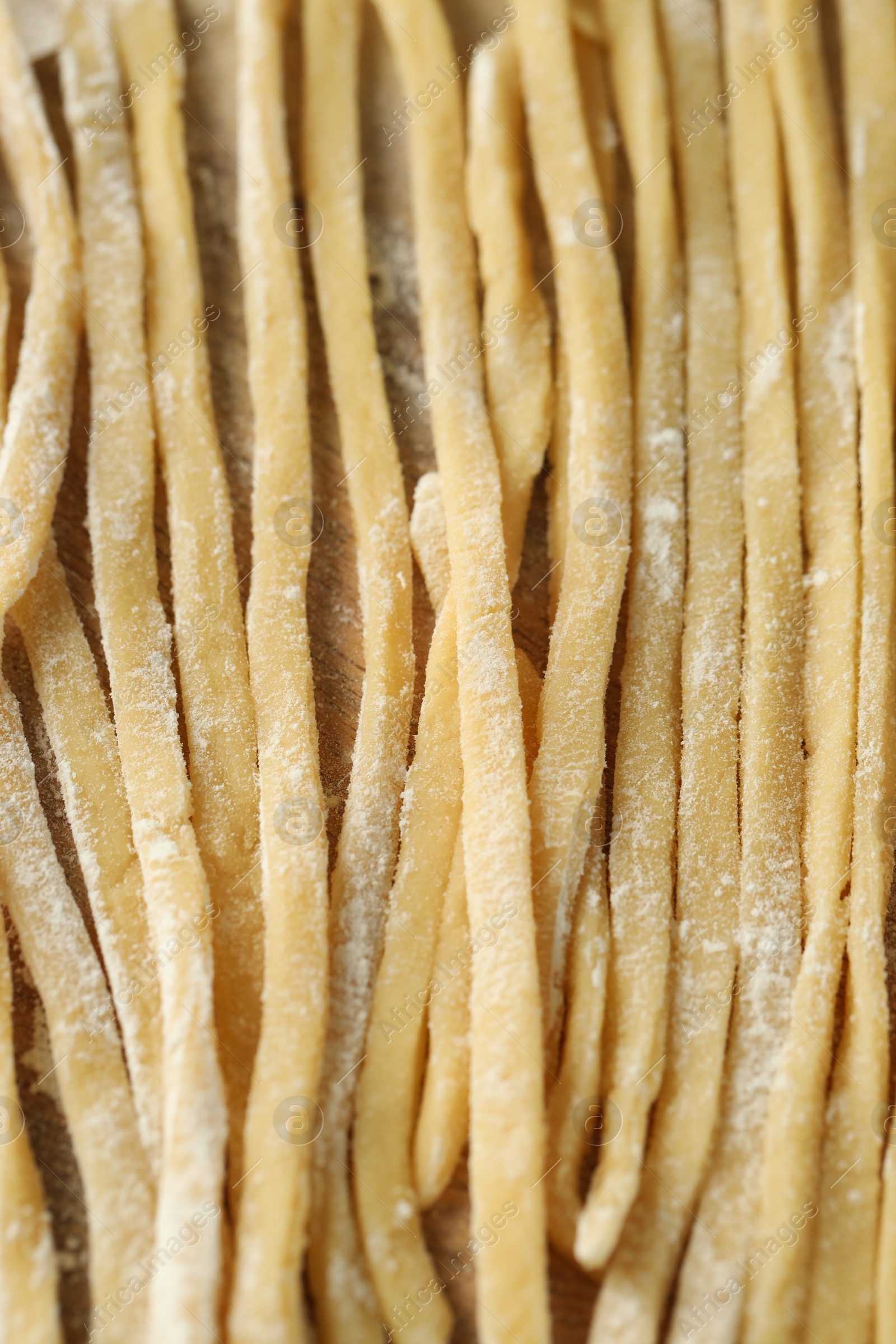 Photo of Raw homemade pasta and flour on wooden table, closeup