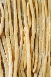 Raw homemade pasta and flour on wooden table, closeup