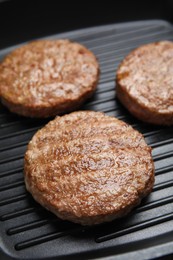Photo of Tasty fried hamburger patties on grill pan, closeup