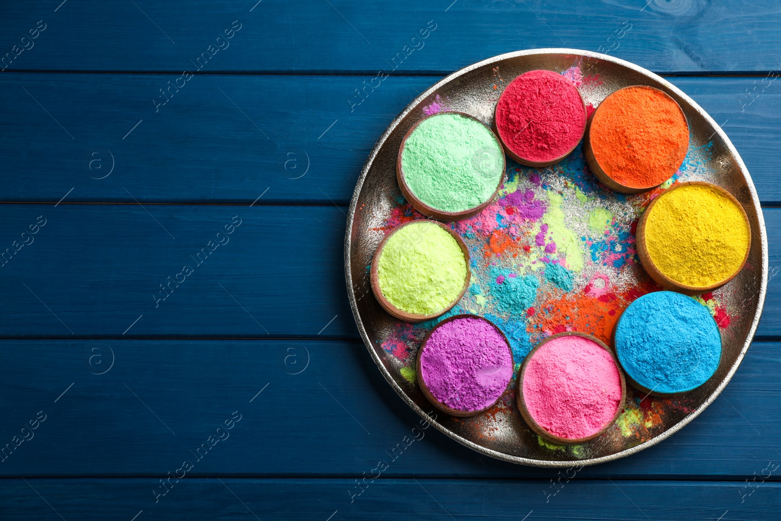 Photo of Colorful powder dyes on blue wooden background, top view with space for text. Holi festival