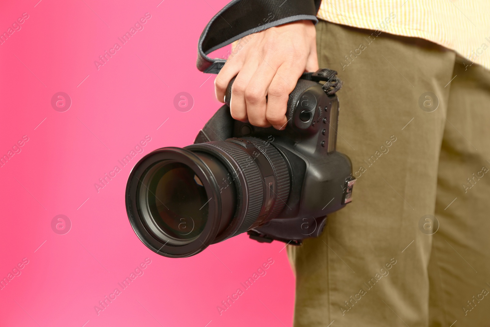 Photo of Professional photographer with modern camera on pink background in studio, closeup. Space for text