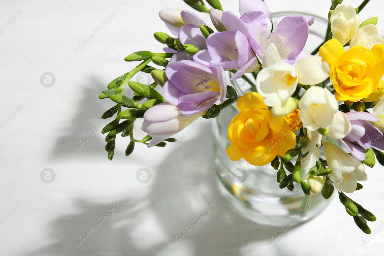 Photo of Bouquet of fresh freesia flowers in vase on table, above view