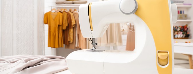 Image of Sewing machine and fabric on table in dressmaking workshop. Banner design with space for text