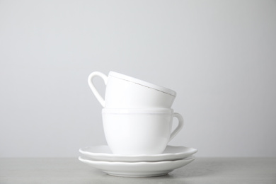Photo of Ceramic saucers and cups on table against white background