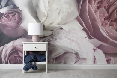 Photo of White nightstand near wall with floral wallpaper, space for text. Stylish room interior