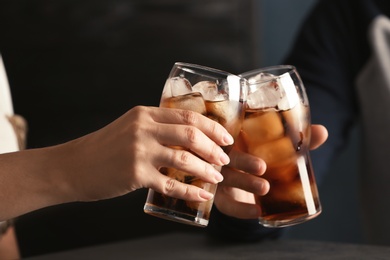 Friends with glasses of tasty refreshing cola at table, closeup view