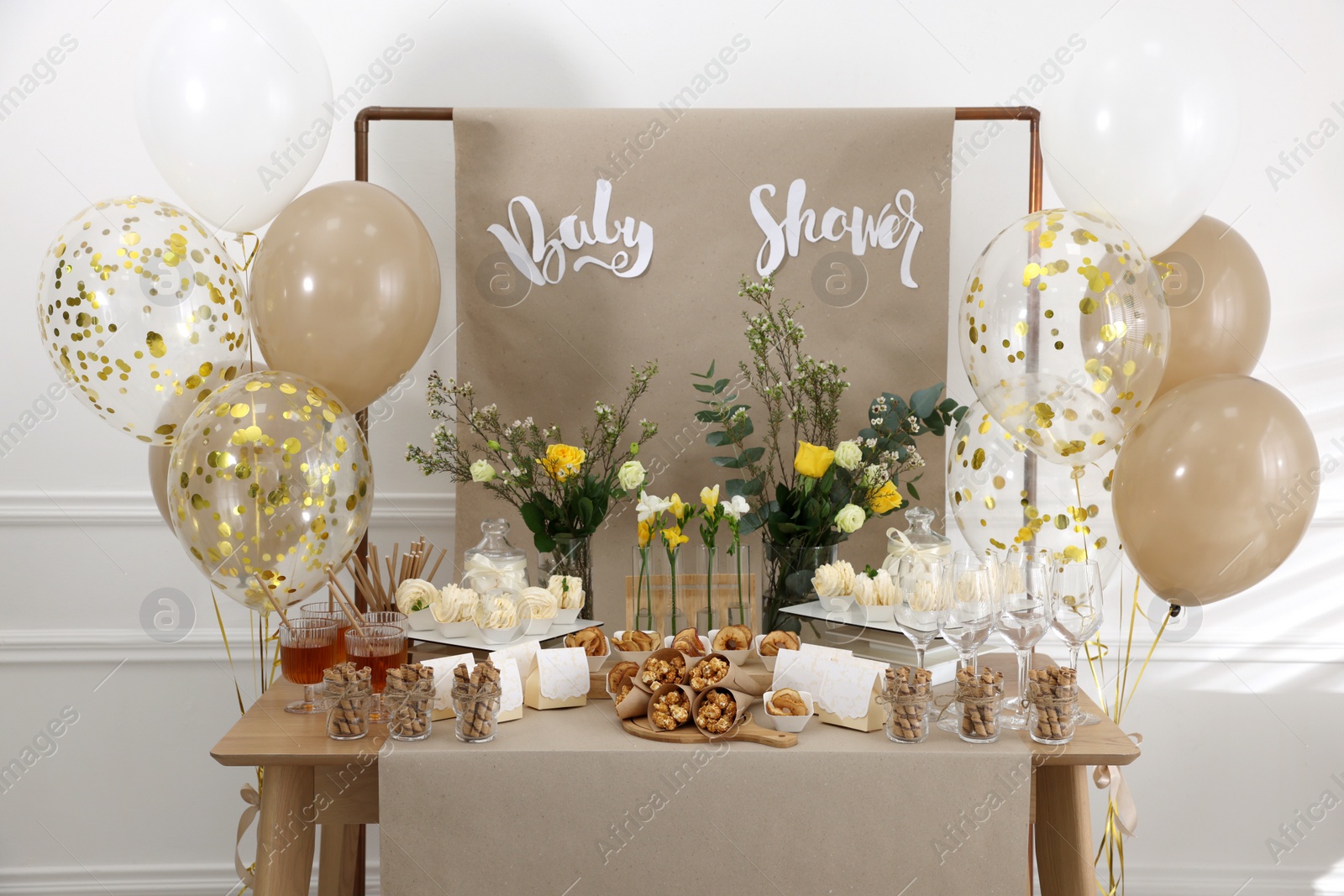 Photo of Tasty treats and glasses of drink on table in room. Baby shower party