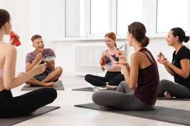 Photo of Group of people eating healthy food after yoga class indoors