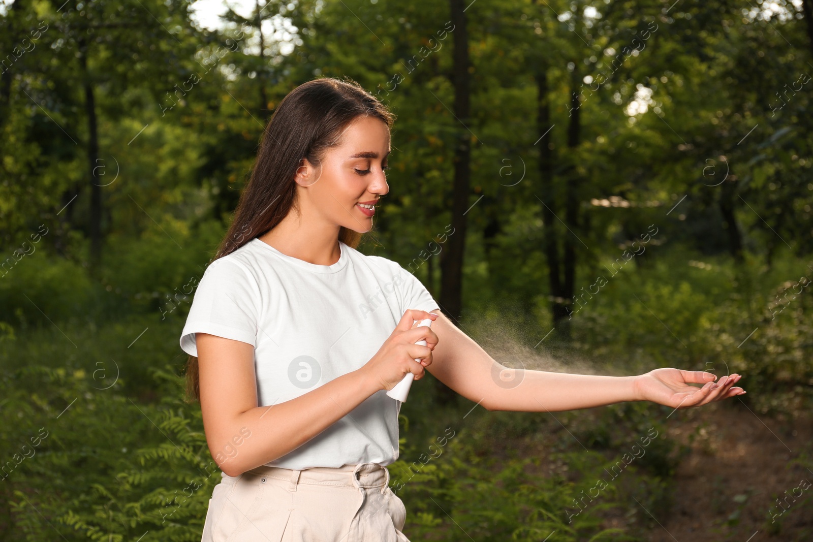 Photo of Woman applying insect repellent on arm in park. Tick bites prevention