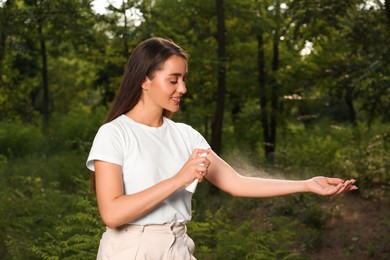 Woman applying insect repellent on arm in park. Tick bites prevention