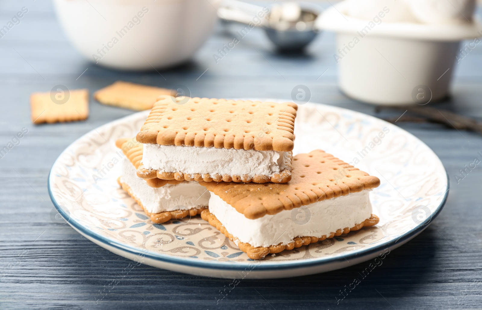 Photo of Sweet delicious ice cream cookie sandwiches on blue wooden table