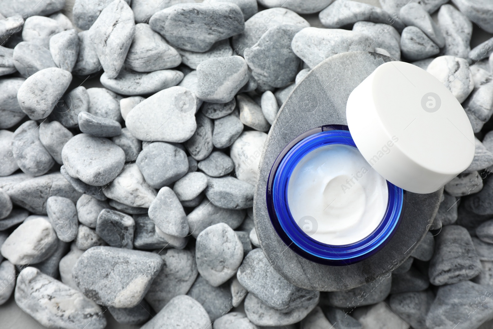 Photo of Jar of moisturizing cream on stones, top view. Space for text