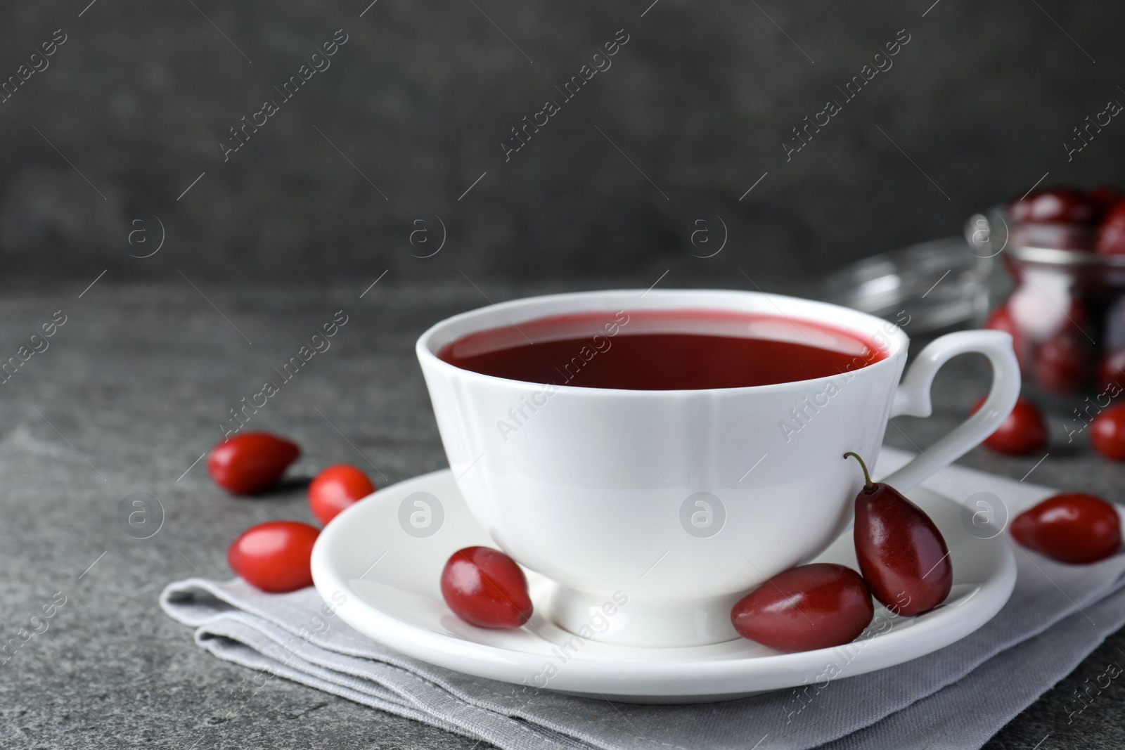 Photo of Cup of fresh dogwood tea and berries on grey table. Space for text