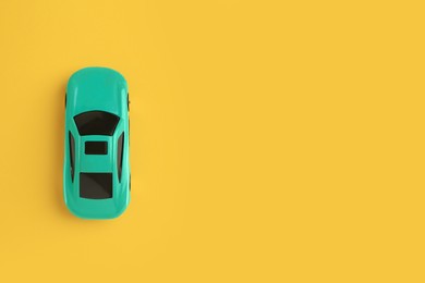 Photo of One turquoise car on yellow background, top view with space for text. Children`s toy