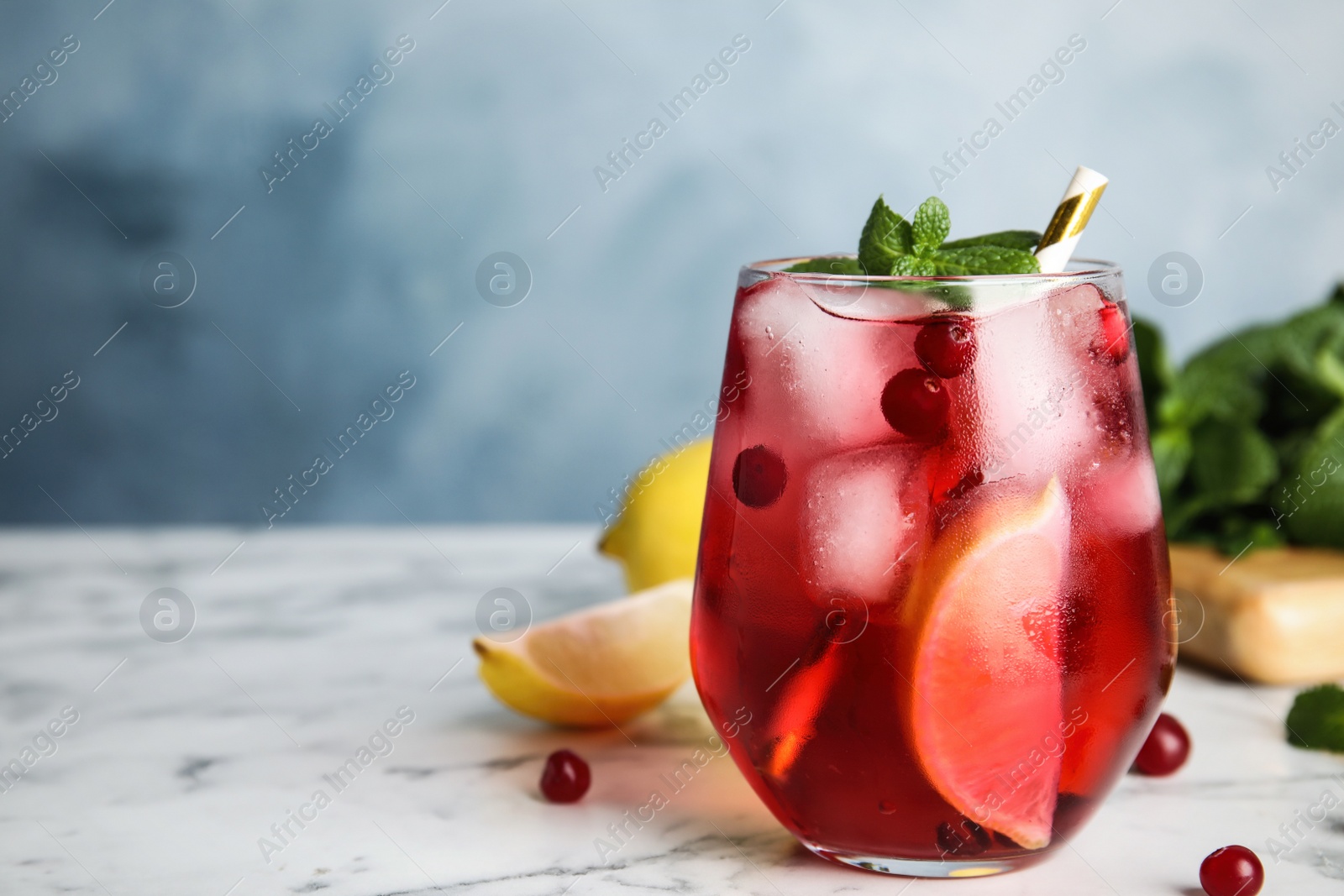 Photo of Tasty refreshing cranberry cocktail with mint on white marble table, closeup. Space for text