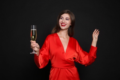 Photo of Happy woman with glass of champagne on black background. Christmas party