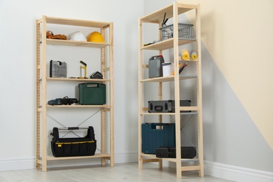 Photo of Wooden shelving units with different instruments near color wall. Stylish room interior