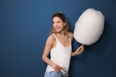 Photo of Portrait of pretty young woman with cotton candy on blue background