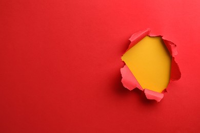 Photo of Hole in red paper on yellow background, space for text