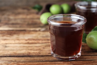 Photo of Delicious liqueur and green walnuts on wooden table. Space for text