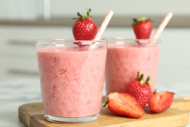 Photo of Tasty strawberry smoothies in glasses on wooden board, closeup