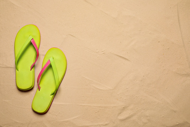 Photo of Green flip flops on sand, flat lay with space for text. Beach accessory
