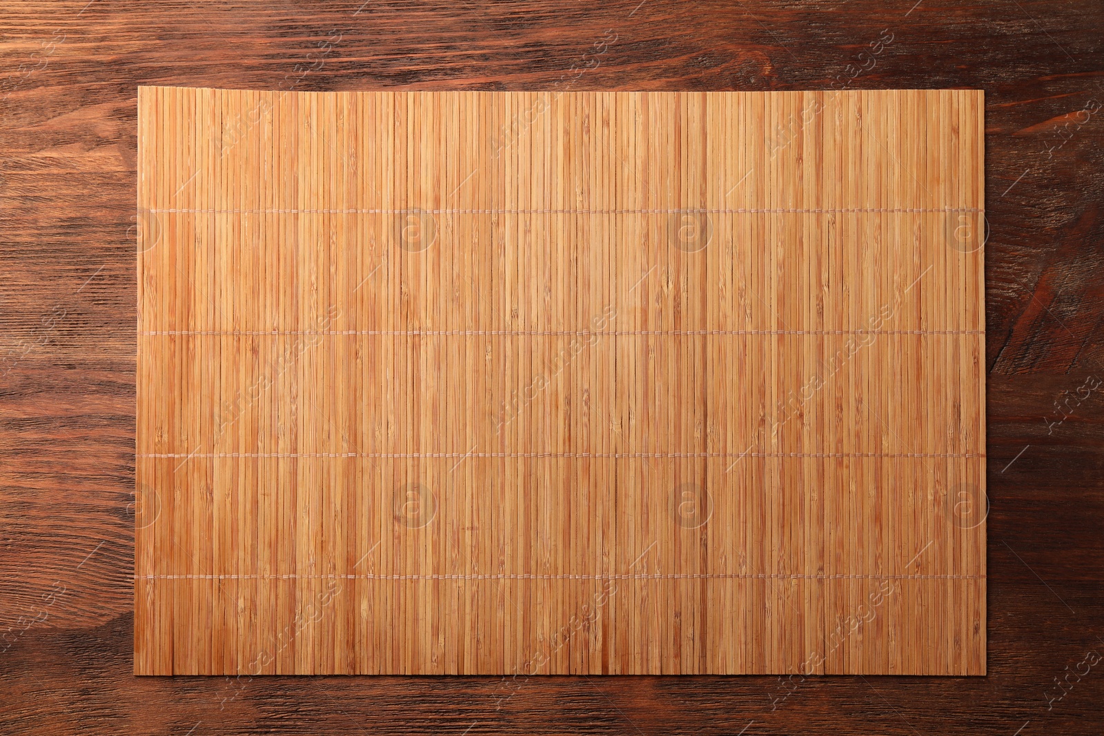 Photo of Bamboo mat on wooden table, top view. Space for text