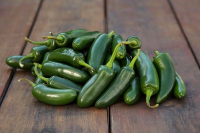 Photo of Pile of fresh green jalapeno peppers on wooden table