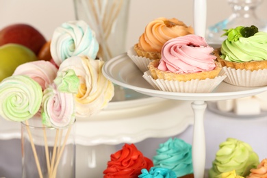 Photo of Delicious cupcakes on stand at candy bar, closeup