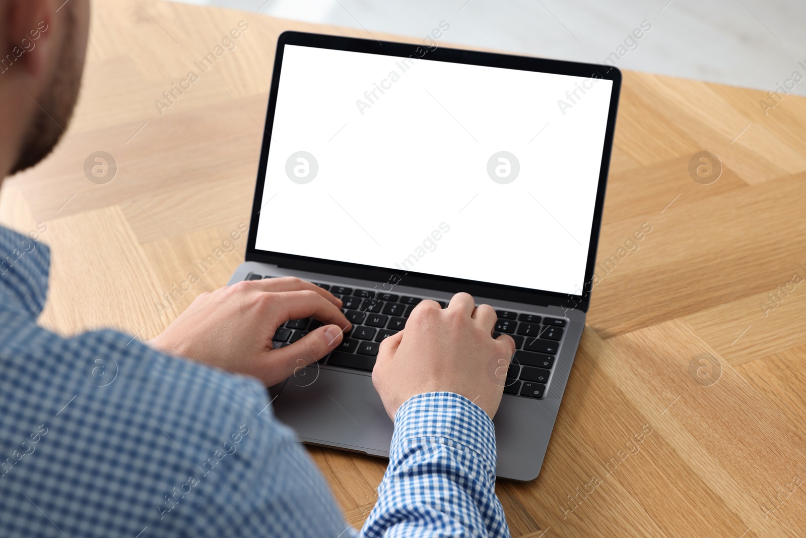 Photo of Man working on laptop at wooden desk, closeup