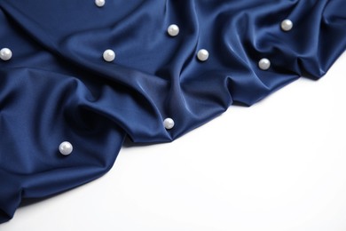 Photo of Texture of delicate dark blue silk with pearls on white background