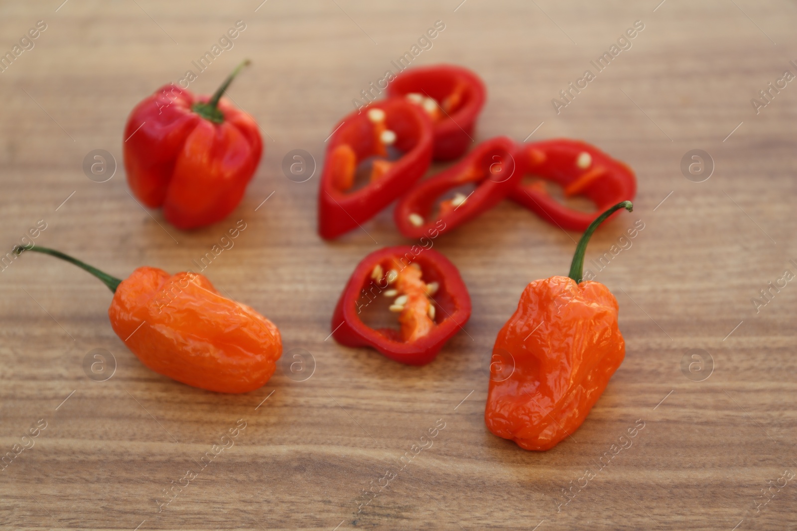 Photo of Whole and cut chili peppers on wooden table