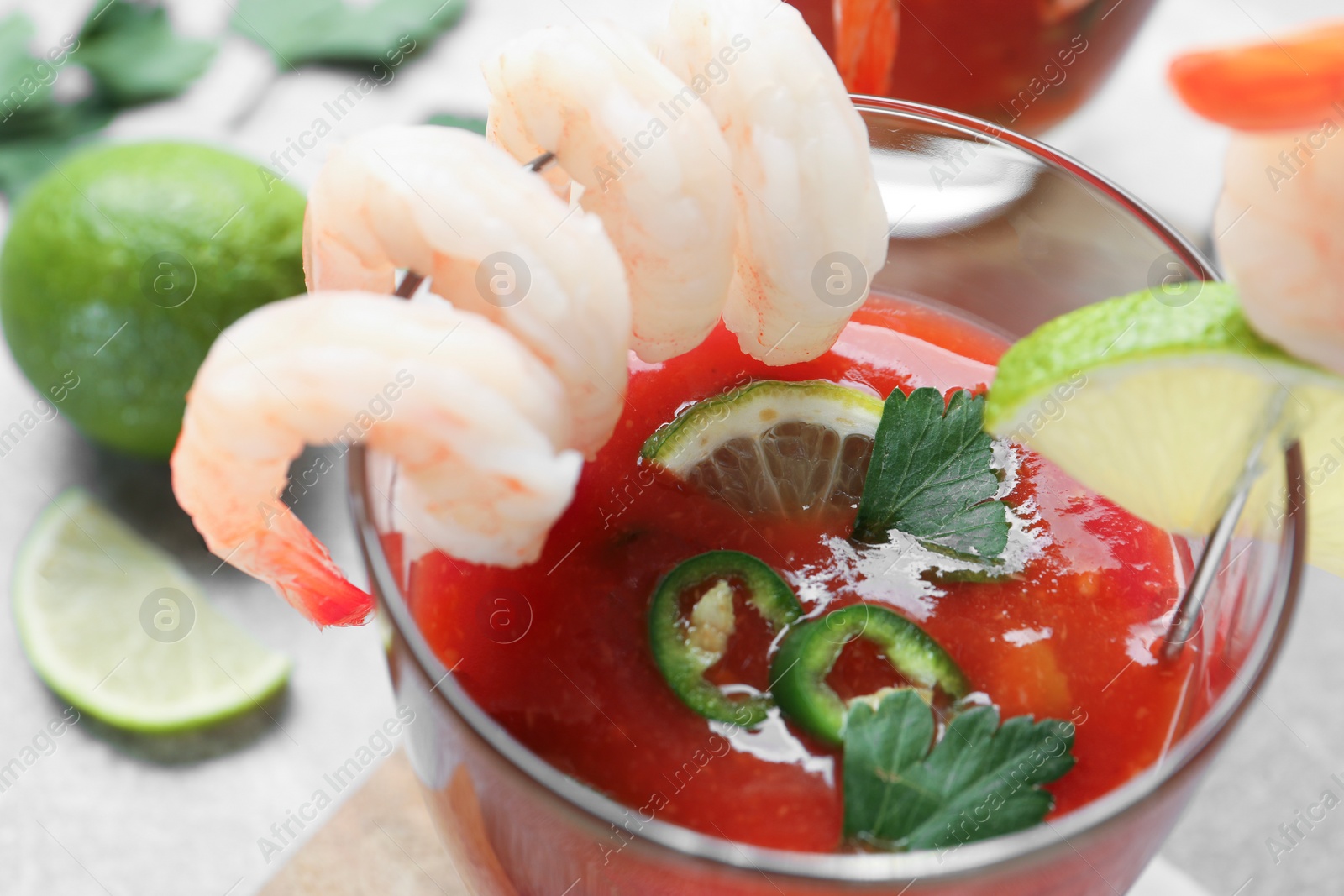 Photo of Tasty shrimp cocktail with sauce and lime in glass on light table, closeup
