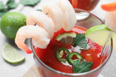 Tasty shrimp cocktail with sauce and lime in glass on light table, closeup