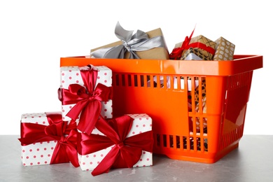 Shopping basket full of gift boxes on light grey marble table against white background