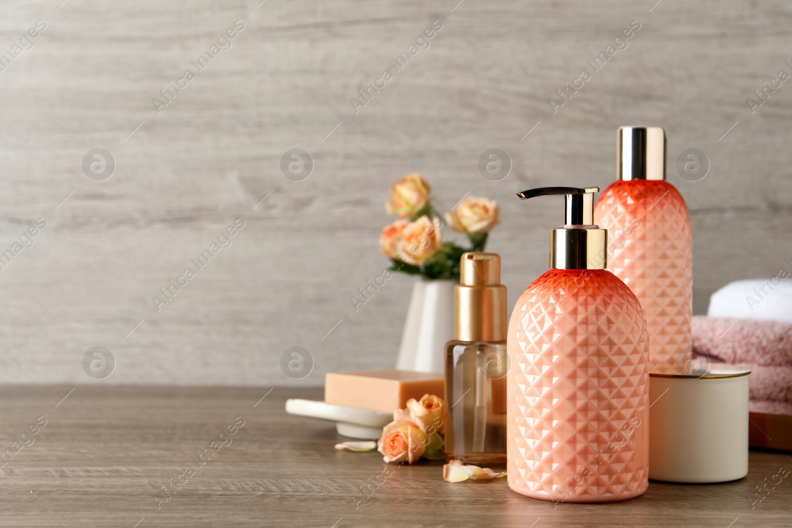 Photo of Stylish dispenser with liquid soap and other bathroom amenities on wooden table, space for text