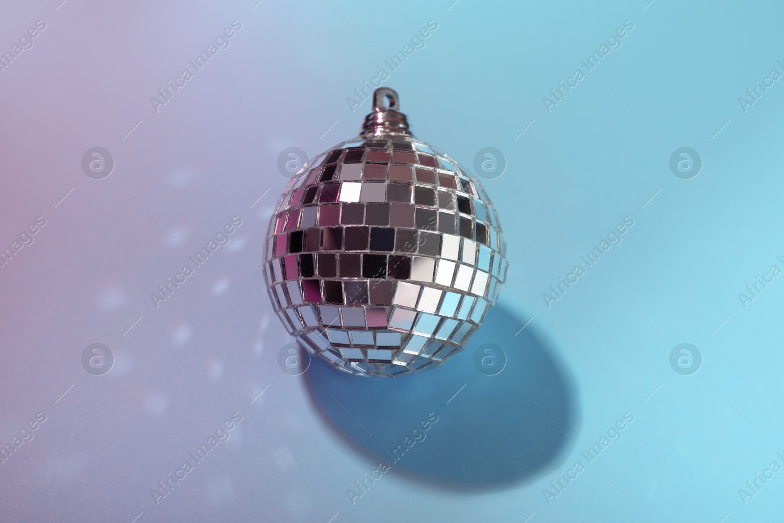 Photo of Shiny disco ball on light blue background, above view