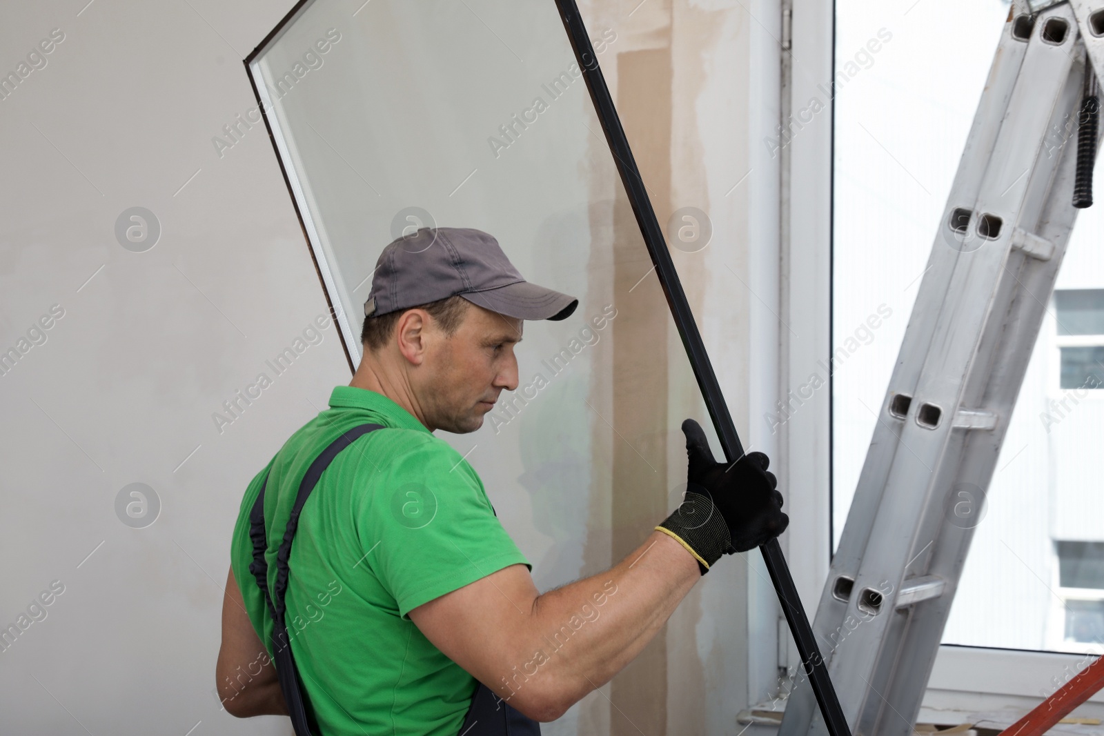 Photo of Worker in uniform installing double glazing window indoors