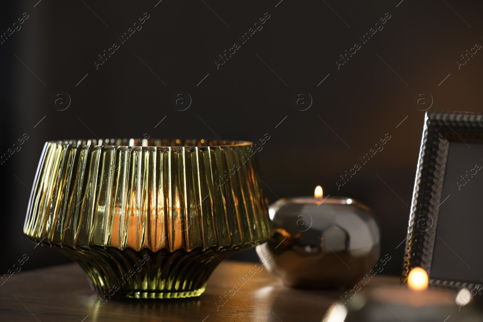 Photo of Stylish lantern with burning candle on wooden table indoors. Space for text