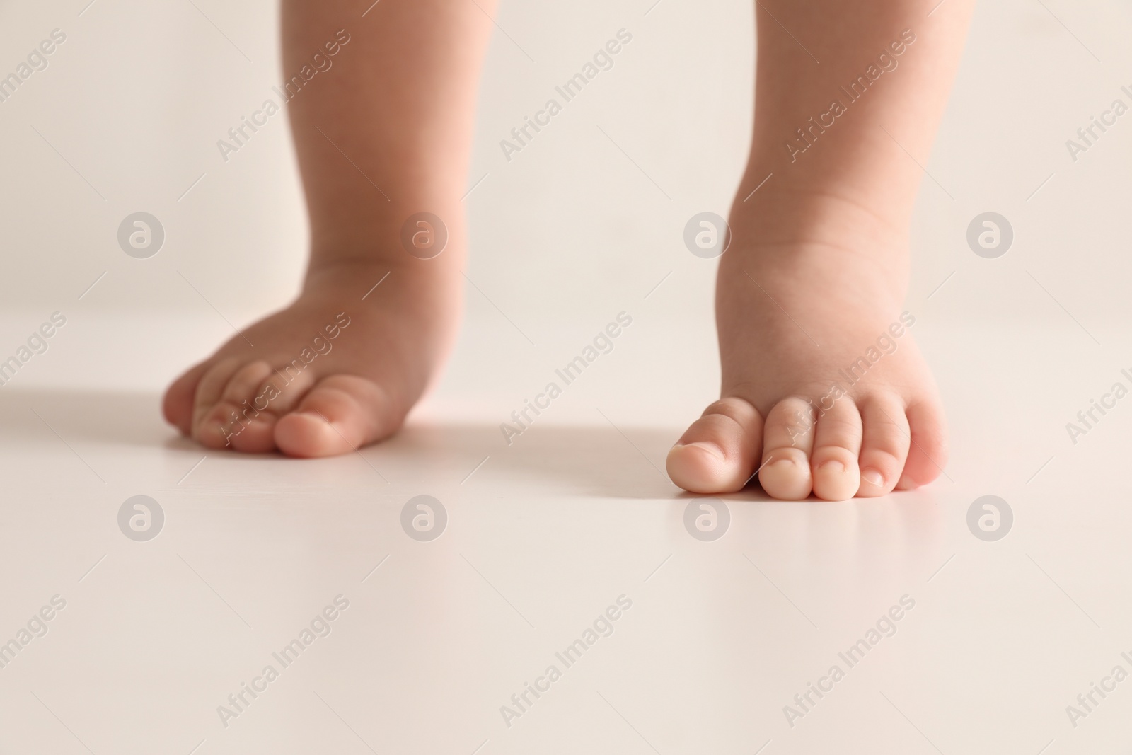 Photo of Little baby on light background, closeup on feet