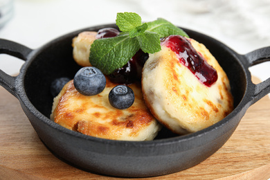 Photo of Delicious cottage cheese pancakes with blueberries, mint and jam in pan