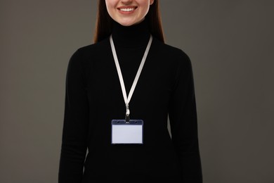 Woman with blank badge on grey background, closeup