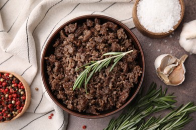 Photo of Fried ground meat in bowl and products on brown textured table, flat lay