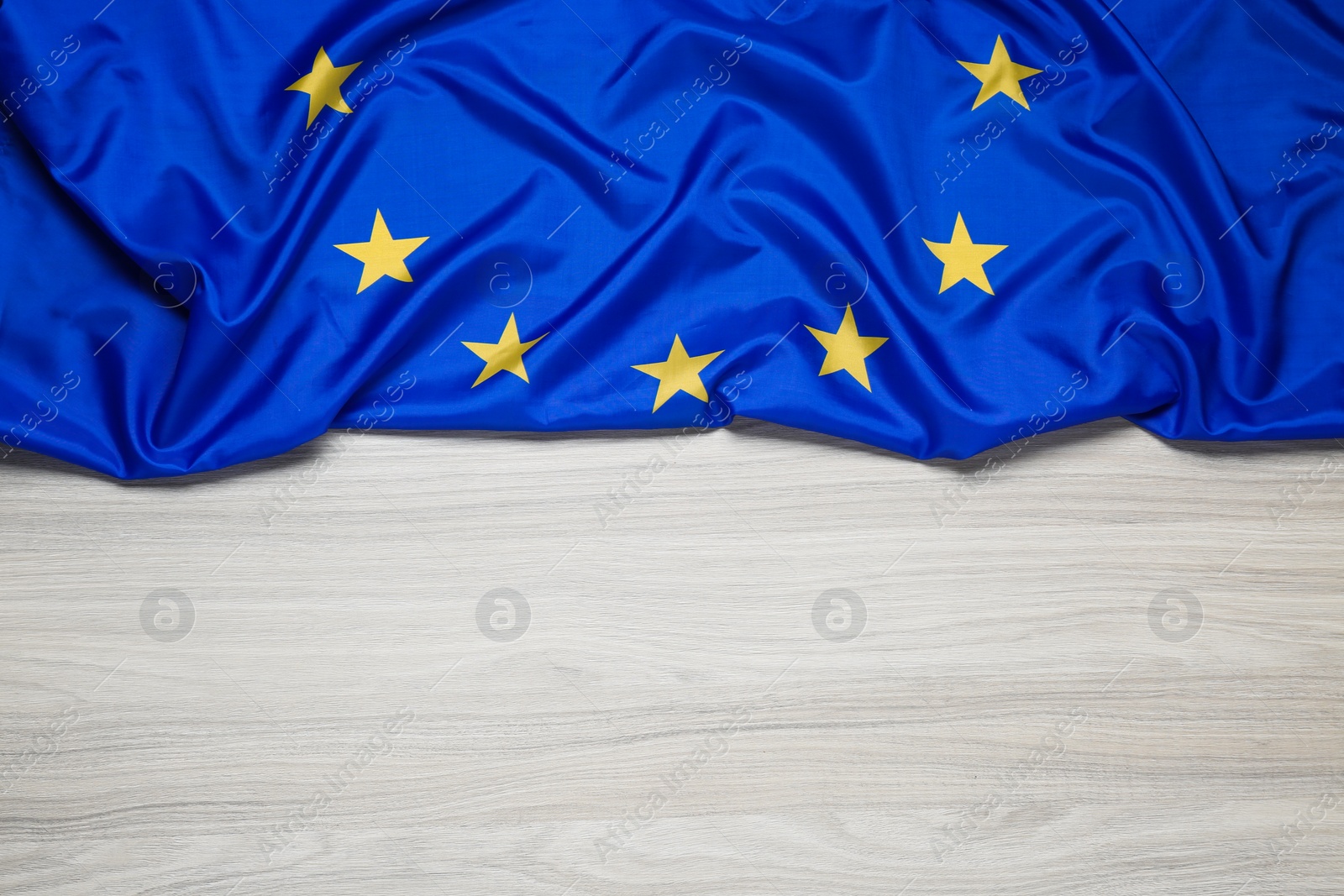 Photo of Flag of European Union on wooden table, top view. Space for text