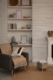 Photo of Comfortable armchair near shelves with different decor in room. Interior design