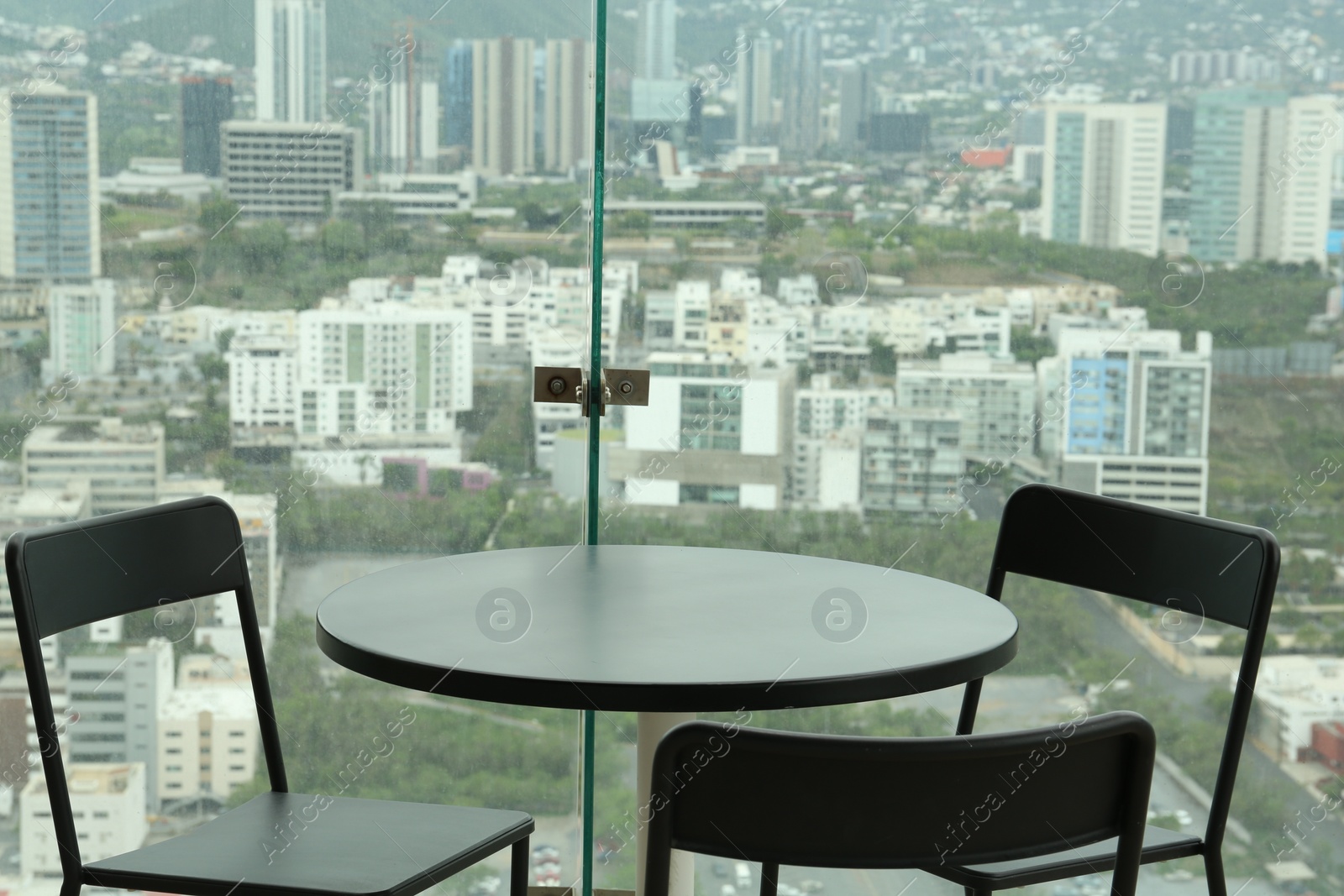 Photo of Coffee table and chairs against picturesque landscape of city in cafe